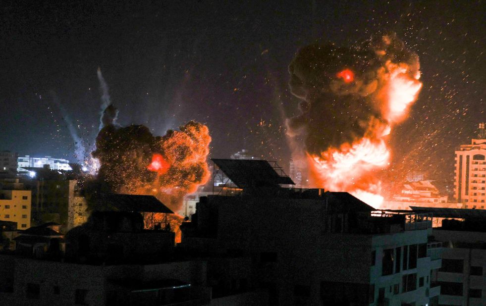 Explosions are seen over buildings in Gaza City as Israeli forces strike targets early on May 18.