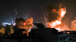 Explosions light-up the night sky above buildings in Gaza City as Israeli forces target the Palestinian enclave with air strikes, early on May 18.