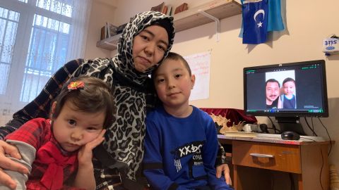 Amannisa Abdullah with daughter, Amina, 3, left, and son Musa, 8. Amina was born in Turkey and has never met her father, Ahmad Talip, pictured on screen in the background with Musa.