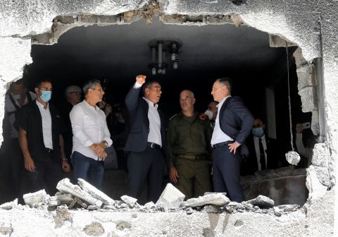 German Foreign Minister Heiko Maas, right, listens to his Israeli counterpart, Gabi Ashkenazi, center, during a visit to a building that was hit by a rocket in Petah Tikva, Israel.