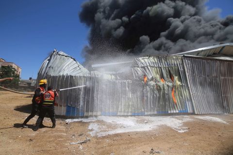 Firefighters work to extinguish a blaze at a warehouse in Rafah, Gaza, after it was hit by Israeli airstrike on May 18.