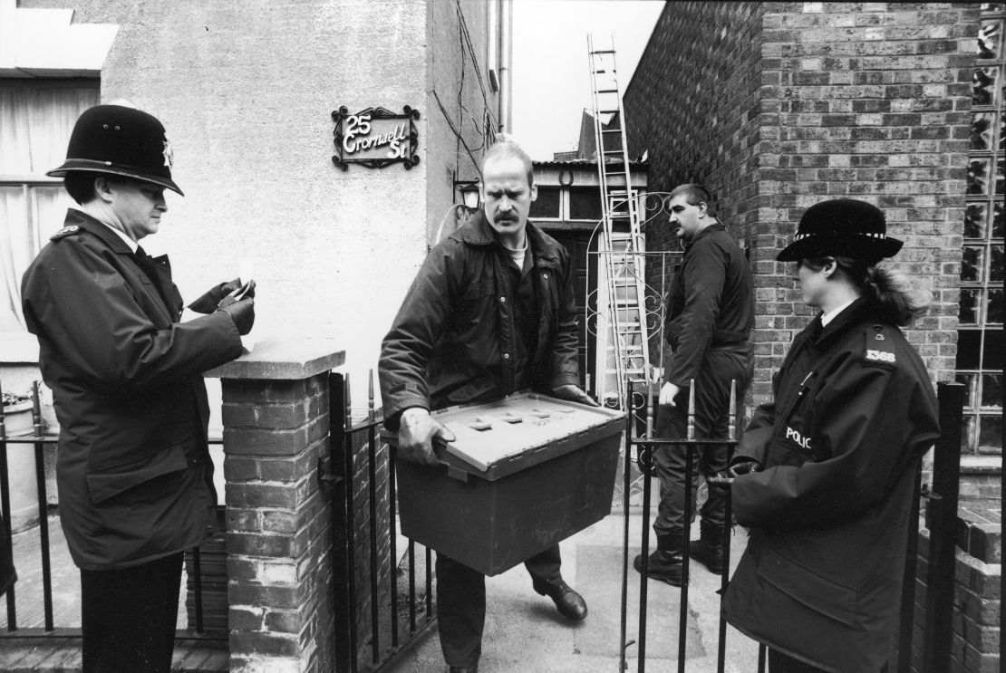 A police investigator walks past a pair of uniformed officers as he carries a large plastic box of evidence from the home of Fred and Rose West at 25 Cromwell Street, Gloucester, England, March 4, 1994.