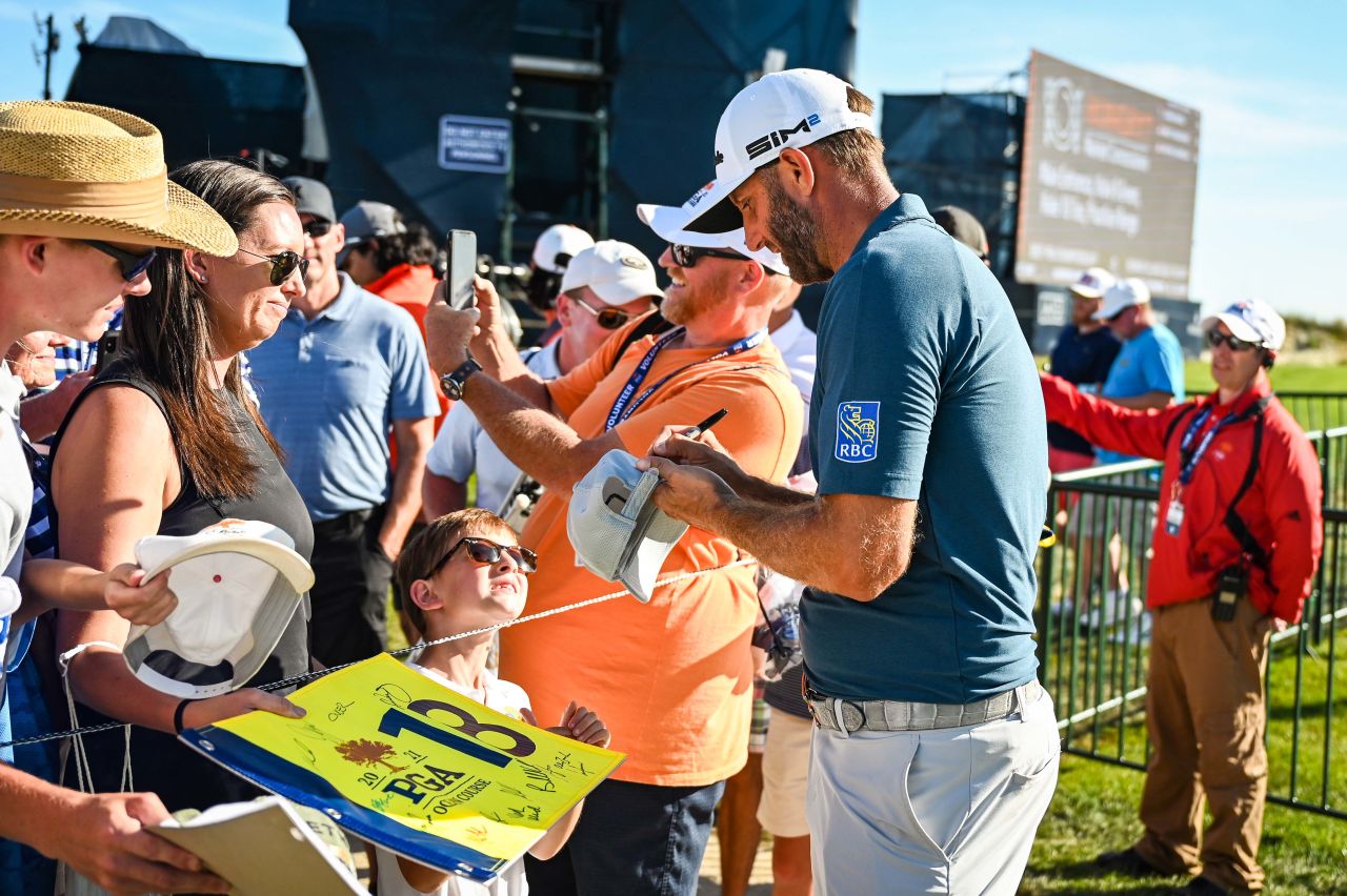 Dustin Johnson signs autographs for fans on the 18th hole during practice.