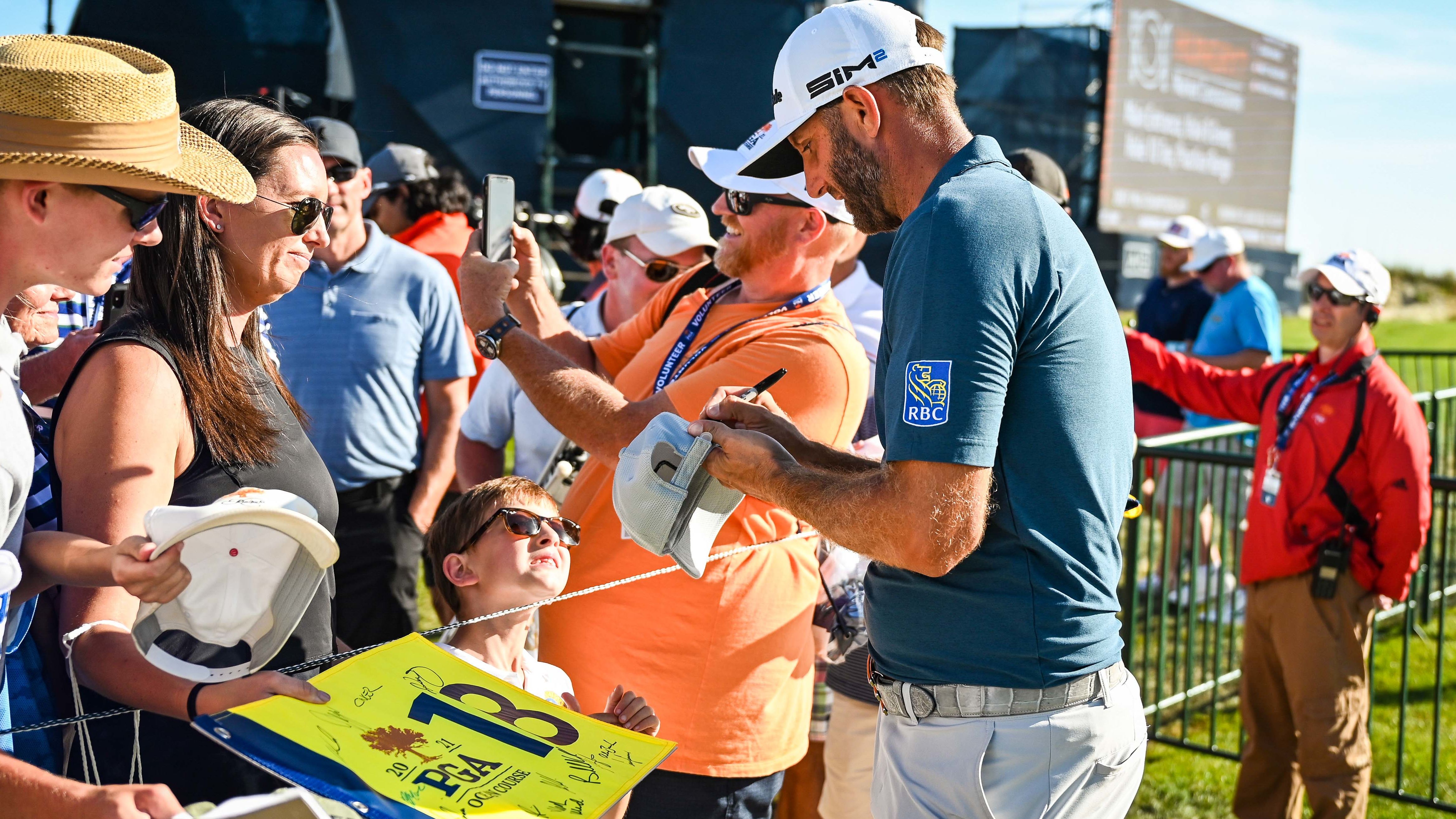 Dustin Johnson signs autographs for fans on the 18th hole during practice.