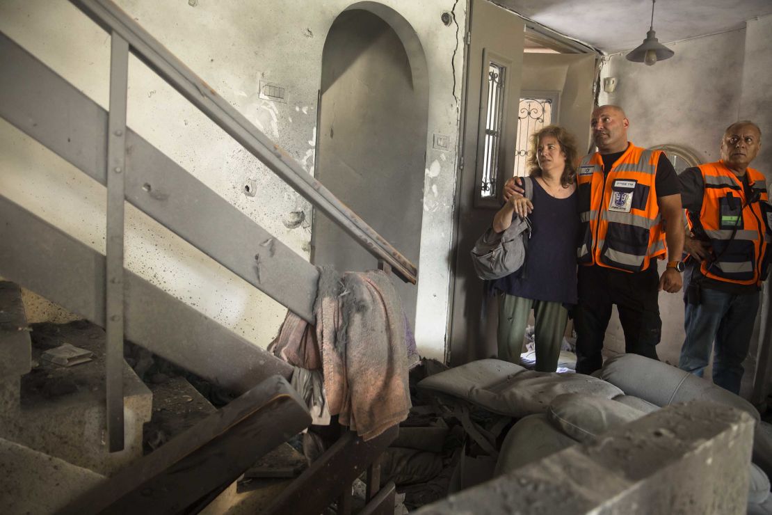 Sigal Ariely, left, inspects the damage to her home, alongside  municipality workers, after a rocket fired from Gaza struck the property in Ashkelon, Israel, on May 20.