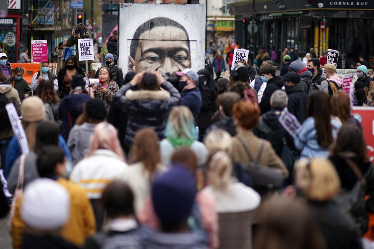 People kneel in front of a Floyd mural during a protest in Manchester, England, on March 27.