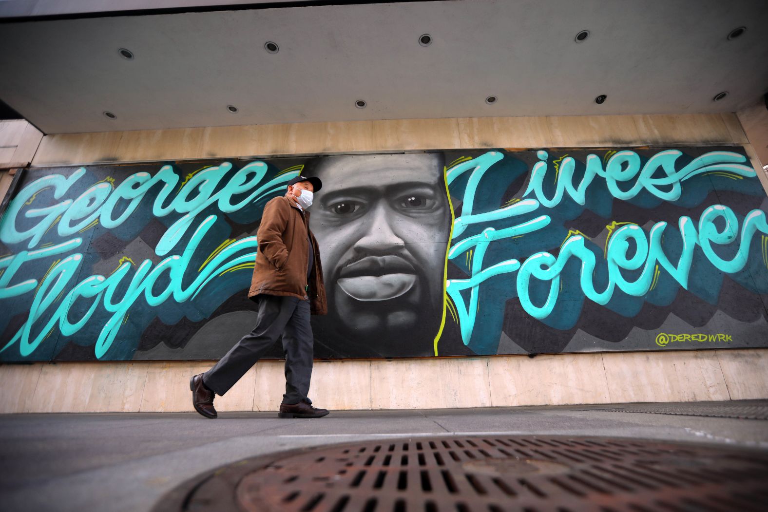 A man walks past a Floyd mural on an office building in Oakland, California, on March 29.