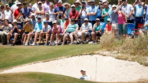 Rory McIlroy plays from a sand area on the 17th green.