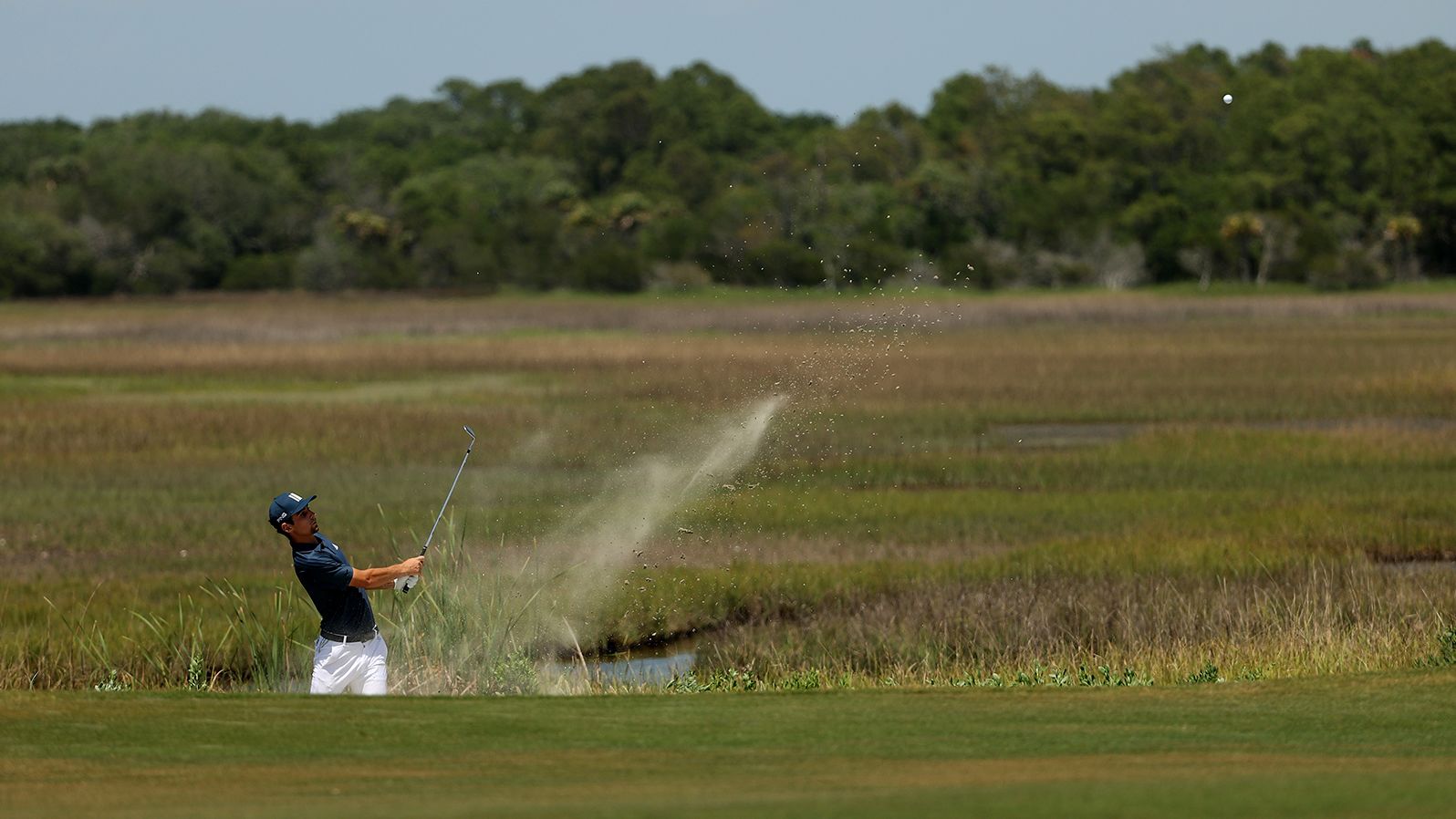 Joaquin Niemann plays a second shot from a sand area on the second hole.