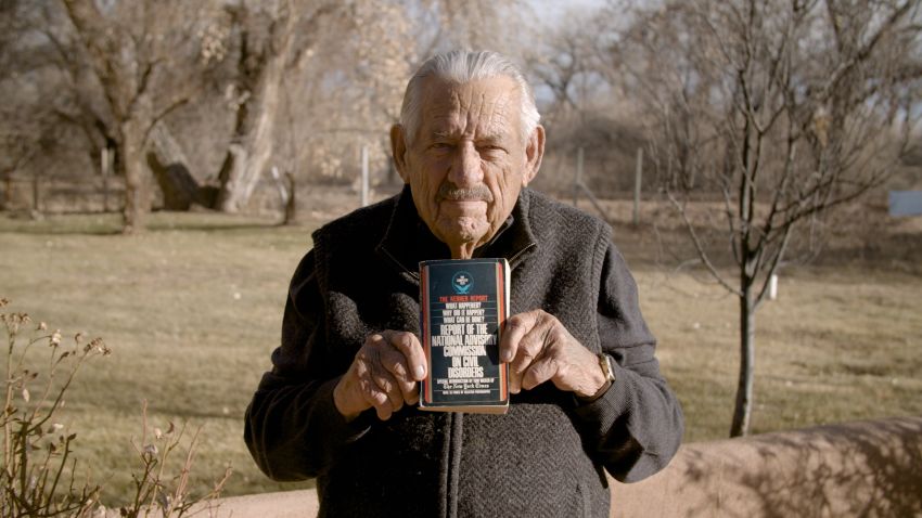 Former Senator Fred Harris holds an original copy of the report of the national advisory commission on civil disorders, also known as the "Kerner Report"