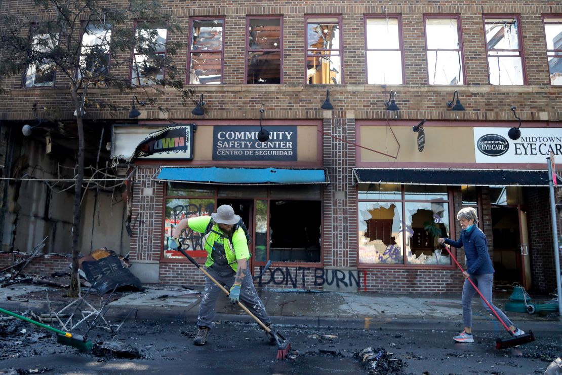 People help cleanup near businesses damaged by protesters on May 30, 2020, in Minneapolis.