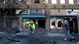 People help cleanup near businesses damaged by protesters, Saturday, May 30, 2020, in Minneapolis. Protests continued following the death of George Floyd, who died after being restrained by Minneapolis police officers on Memorial Day. (AP Photo/Julio Cortez)