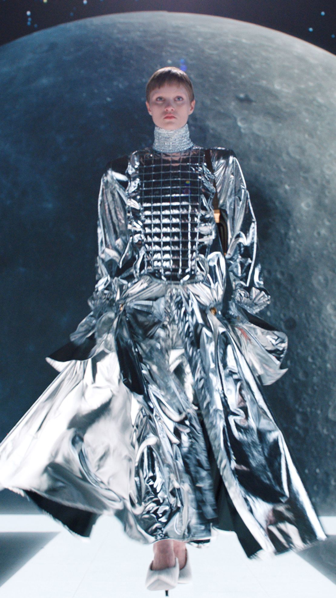 Models carried duffel bags and suitcases as they marched down a luminous catwalk that looped around the moon.