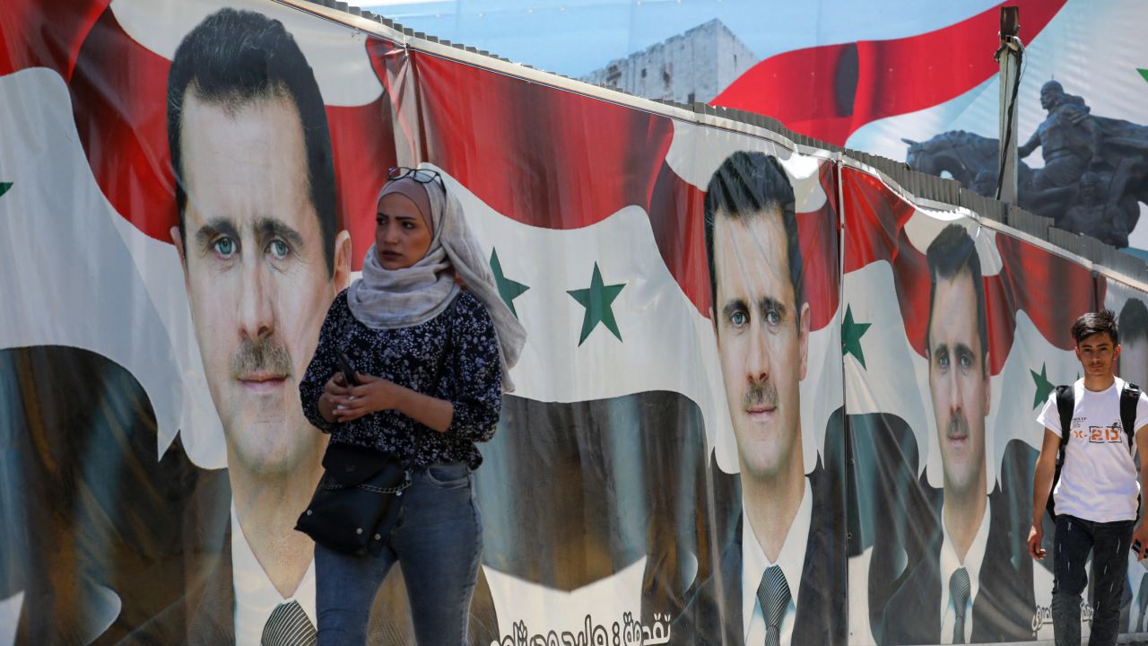 Syrians walk past election campaign billboards for President Bashar al-Assad in Damascus.  