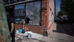 A man boards up a broken window to a barber shop after shots were fired in George Floyd Square on the one year anniversary of George Floyd's death on Tuesday, May 25, 2021, in Minneapolis.  The intersection where George Floyd died was disrupted by gunfire Tuesday, just hours before it was to be the site of a family-friendly street festival marking the anniversary of his death at the hands of police.(AP Photo/Christian Monterrosa)