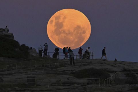 People watch the moon rise over Sydney's Bondi Beach.