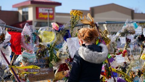 A visitor looks over tributes as they hang on the temporary fence around the parking lot in front of the King Soopers store in which 10 people were killed in March mass shooting on April 9, 2021