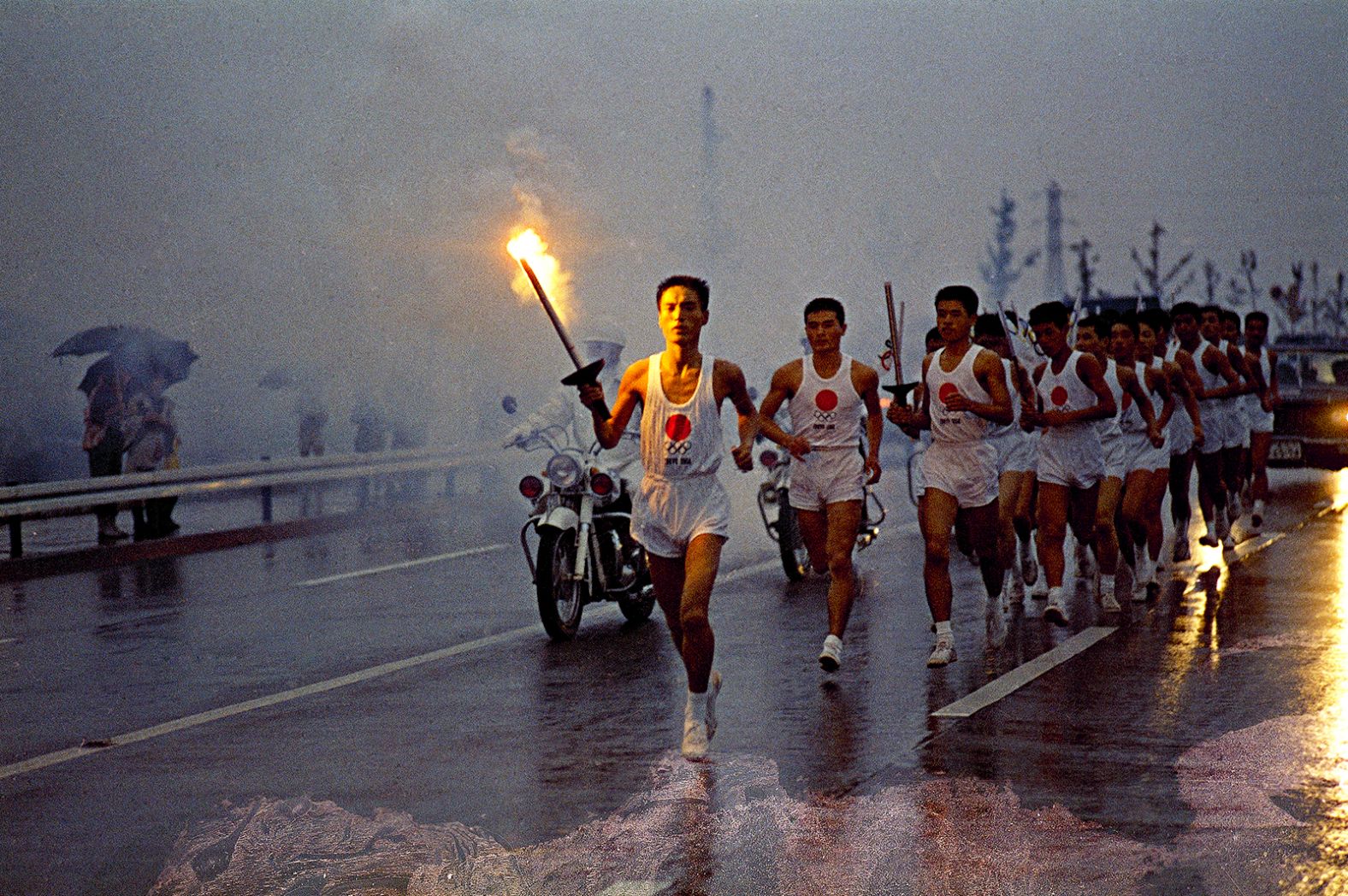 Torchbearers run through the rain on their way to the National Stadium in Tokyo in October 1964.