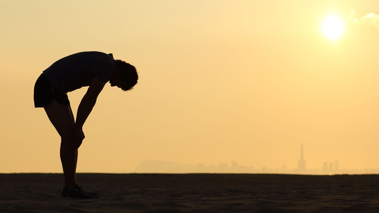 Silhouette of an exhausted sportsman at sunset with the horizon in the background