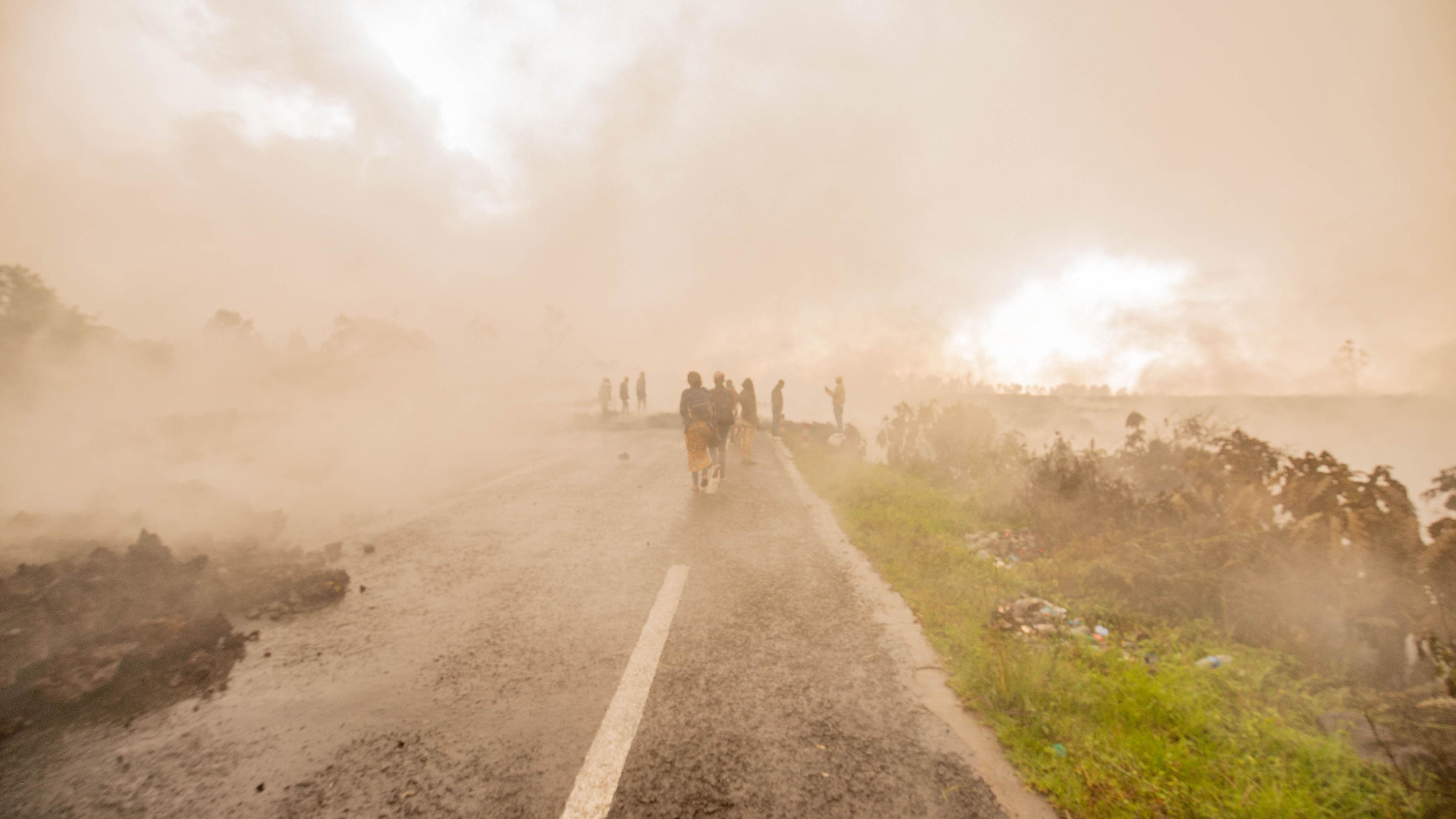 Goma residents walk through smoke from smoldering lava on May 23.