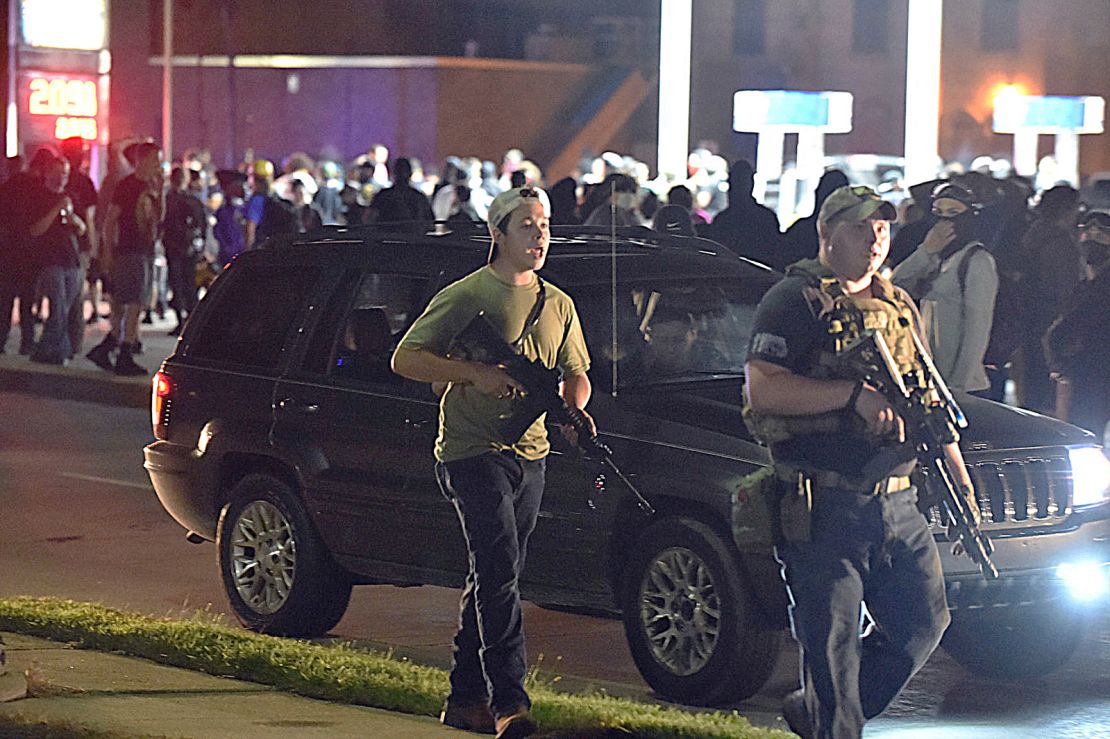 Kyle Rittenhouse, left, with backwards cap, in Kenosha, Wisconsin, with another armed civilian during chaotic protests in August 2020 over the police shooting of Jacob Blake, a Black man. Rittenhouse is accused of killing two people during the protests.