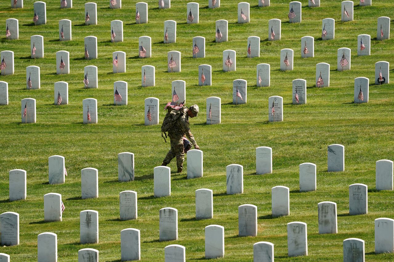 A US soldier places a flag as part of the Flags In ceremony at Arlington National Cemetery on Thursday, May 27. More than 1,000 service members placed flags in front of more than 260,000 headstones.