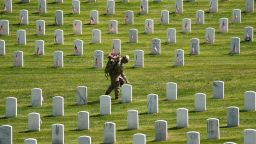 A member of the Armed Forces takes part in the Flags-In ceremony, where more than 1,000 service members place flags in front of more than 260,000 headstones on May 27, 2021, in Arlington National Cemetery in Arlington, Virginia.