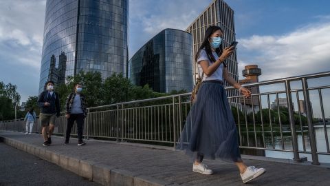 People wear protective masks as they walk across a bridge over the Liangma river on May 24 in Beijing, China.