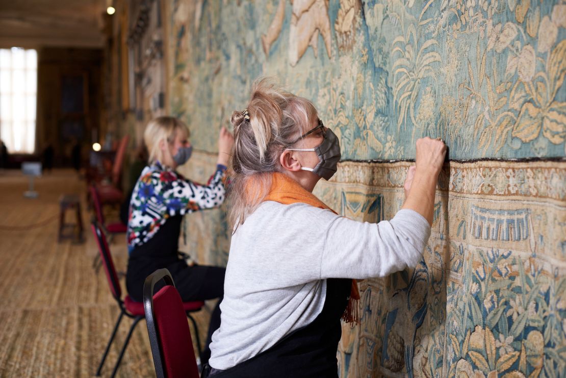 Textile conservators from the National Trust working on one of the many tapestries at the center of the restoration project.