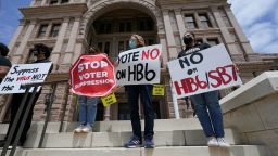 In this April 21, 2021 file photo, people opposed to Texas voter bills HB6 and SB7 hold signs during a news conference hosted by Texas Rising Action on the steps of the State Capitol in Austin, Texas. 