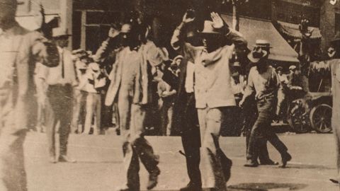 This photograph shows men walking with their hands raised during the Tulsa race massacre on June 1, 1921.