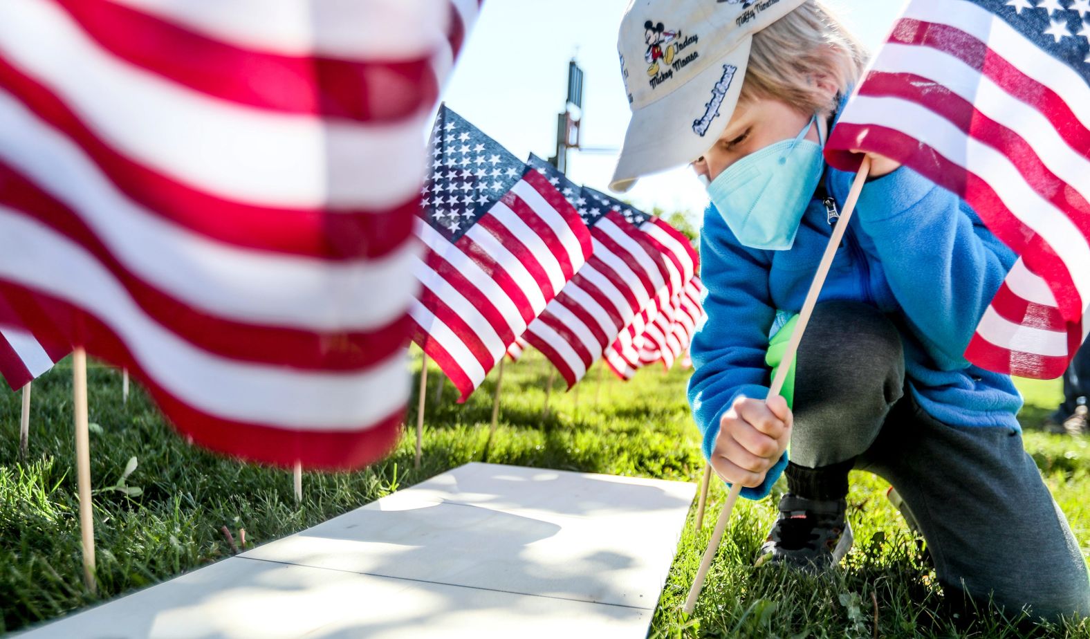 Elias Loosen plants a flag Saturday as part of the War Memorial Center's Field of Flags community event in Milwaukee.