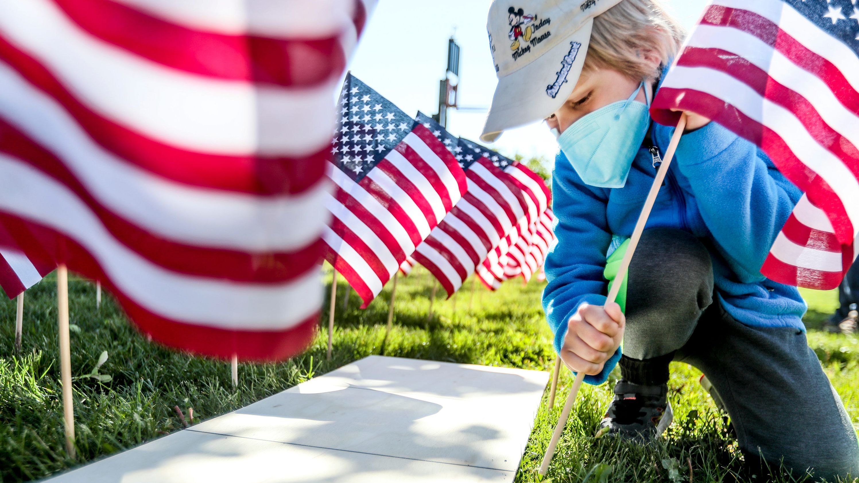 Elias Loosen plants a flag Saturday as part of the War Memorial Center's Field of Flags community event in Milwaukee.