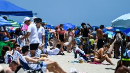 People relax on the sand during the Memorial Day Hyundai Air and Sea Show in Miami Beach, Florida on May 29, 2021. - The Hyundai Air & Sea Show showcases the women, men, technology, and equipment from all five branches of the United States military.