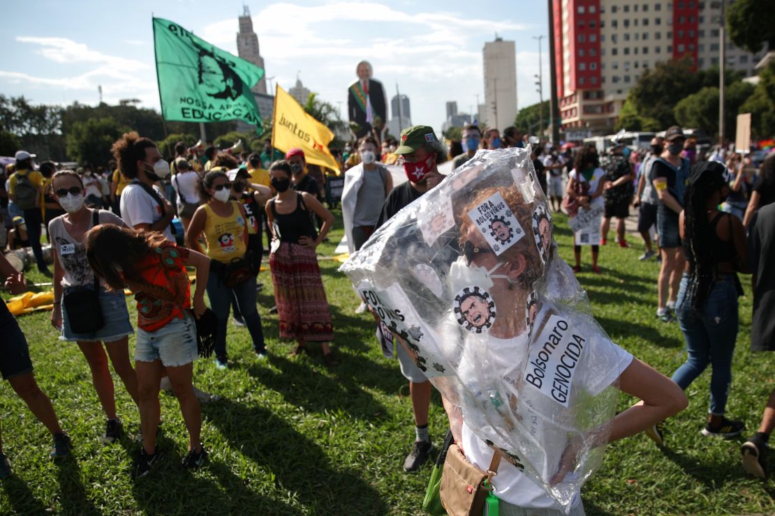 A protester wears a sign accusing Bolsonaro of genocide.