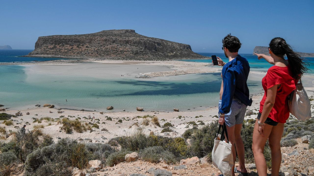 A couple of tourists looks at the Balos beach and its lagoon in the north west of the island of Crete, on May 13, 2021. - Greece easies the Covid-19 measures in welcoming international tourists on May 14. (Photo by Louisa GOULIAMAKI / AFP) (Photo by LOUISA GOULIAMAKI/AFP via Getty Images)