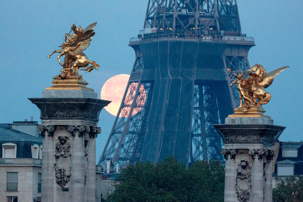 A supermoon sets behind the Eiffel Tower in Paris on April 27, 2021. France has also eased restrictions for some overseas visitors.