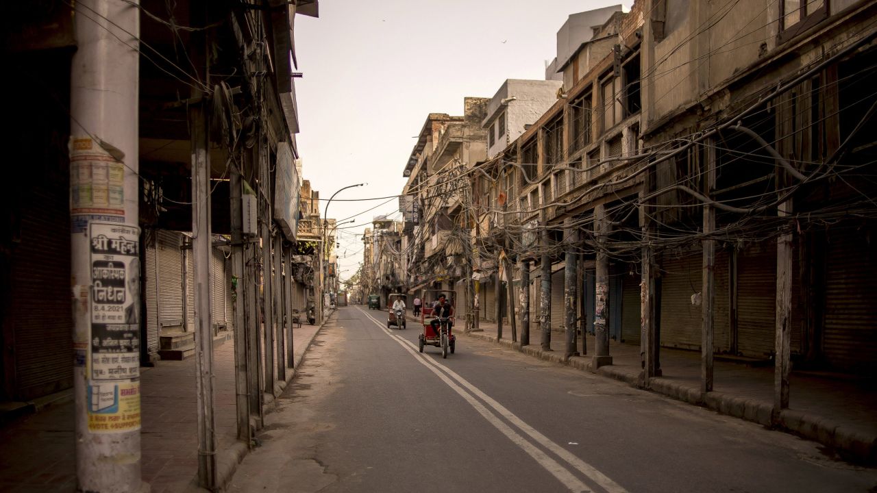 Electric rickshaws pass closed stores on a deserted street during lockdown restrictions in New Delhi on May 31, 2021.
