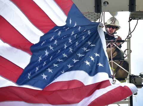 Michael Cosgrove, deputy chief of the Rose Tree Fire Company, unfurls an American flag before the start of Memorial Day services in Rose Tree, Pennsylvania, on Monday, May 31.