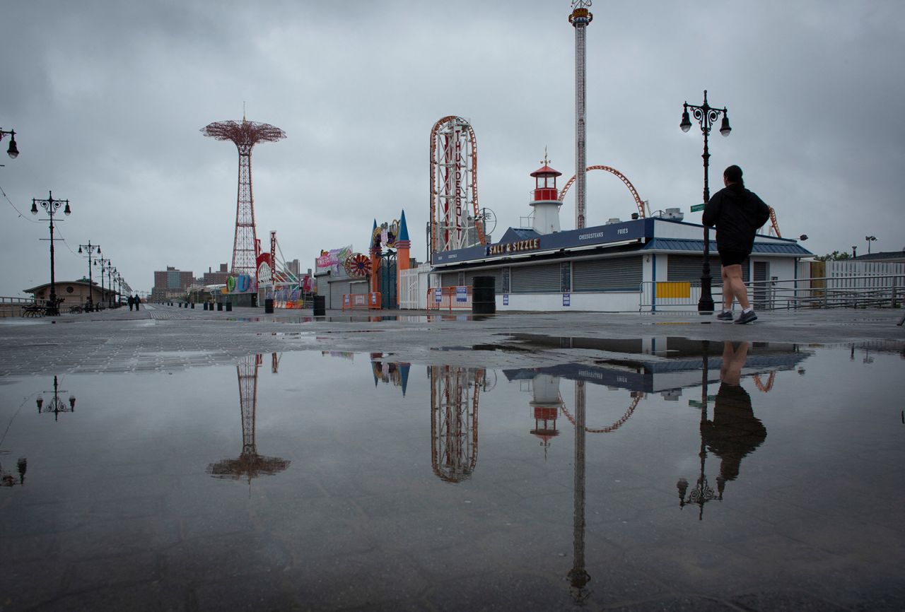 People visit the Coney Island boardwalk as rain falls in New York on Sunday.