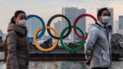 TOKYO, JAPAN - JANUARY 22: People wearing face masks walk past the Olympic Rings on January 22, 2021 in T