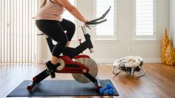 A young mother exercising in her home on an exercise bike.