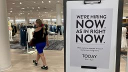 A customer walks behind a sign at a Nordstrom store seeking employees, Friday, May 21, 2021, in Coral Gables, Fla.  The number of Americans seeking unemployment benefits dropped last week to 406,000, a new pandemic low and more evidence that the job market is strengthening as the virus wanes and economy further reopens. (AP Photo/Marta Lavandier)