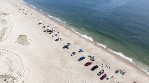 Vehicles are seen parked on the beach as beachgoers enjoy a warm summer day in Rehoboth Beach last summer.