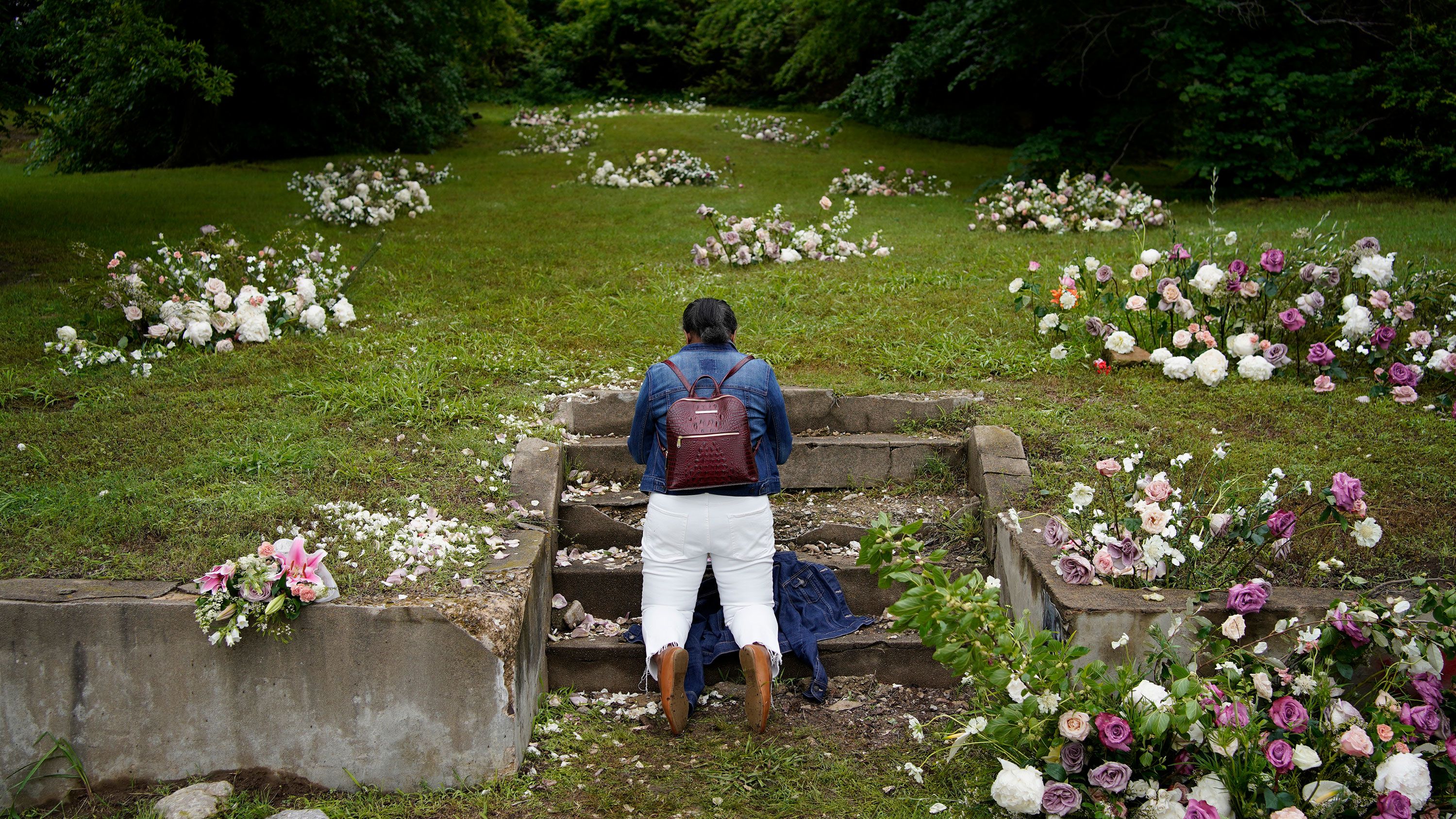 Linda Porter of Birmingham, Alabama, kneels at a makeshift memorial of flowers for the Tulsa Race Massacre at stairs leading to a now empty lot near the historic Greenwood district during centennial commemorations on Tuesday in Tulsa.