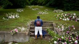 Linda Porter of Birmingham, Ala., kneels at a makeshift memorial of flowers for the Tulsa Race Massacre at stairs leading to a now empty lot near the historic Greenwood district during centennial commemorations of the massacre, Tuesday, June 1, 2021, in Tulsa, Okla. "We came to remember," said Porter, who came to Tulsa for the centennial commemorations. (AP Photo/John Locher)