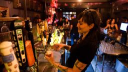 A bartender pours beers for fully vaccinated customers at the bar inside Risky Business, that was once The Other Door but closed during the Covid-19 pandemic in the North Hollywood neighborhood of Los Angeles, California on May 21, 2021. - In order to go inside Risky Business, members must present their original vaccination card after being fully vaccinated, paying a small membership fee, signing a risk release form with penalties for lying, and waiting a full two weeks after competing their shots. While the policy is strict, once inside customers can enjoy an experience knowing that everyone else has been 100-percent vaccinated with an lively pre-pandemic atmosphere with people up close and personal - talking, hugging, playing pool and drinking without rules for masks or social distancing. 