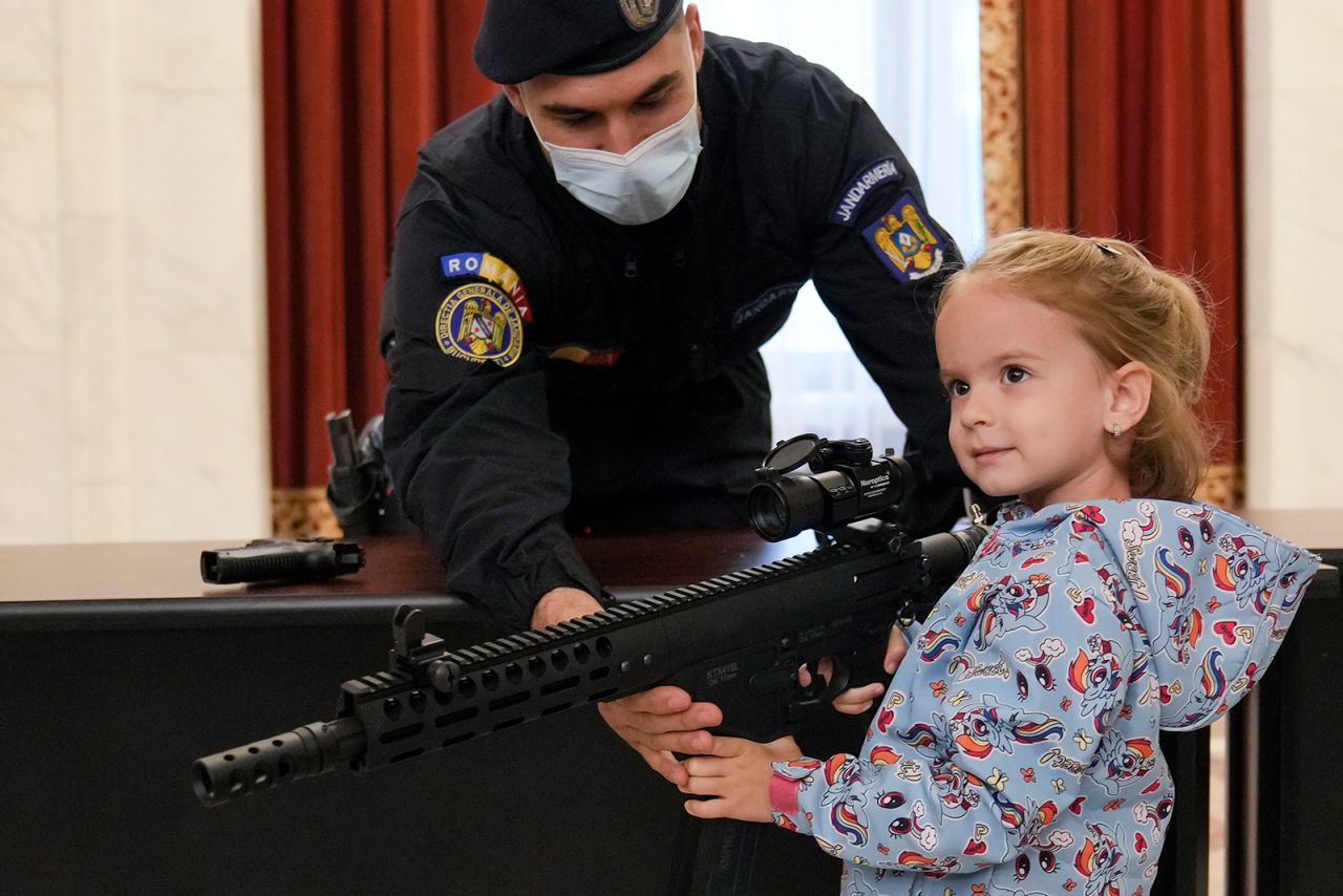A girl poses with a gun at a stand set up by Romania's gendarmerie at the Palace of the Parliament in Bucharest on Tuesday, June 1. People were visiting the building for free because it was Children's Day in Romania.