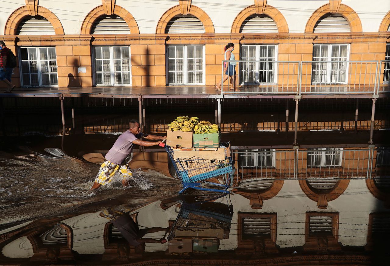 A man pushes a shopping cart loaded with bananas through a flooded street in Manaus, Brazil, on Tuesday, June 1. Rivers around the city have swelled to levels unseen in over a century of record-keeping, according to data published Tuesday by Manaus' port authorities.