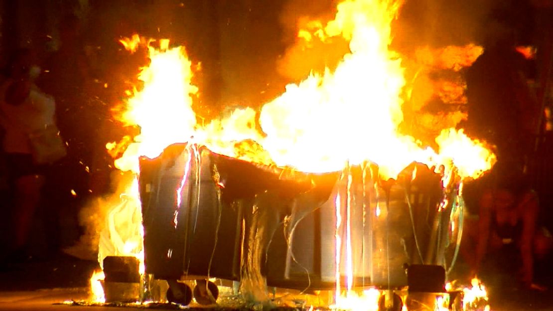 A trash container burns in the middle of a Minneapolis intersection on Thursday night.